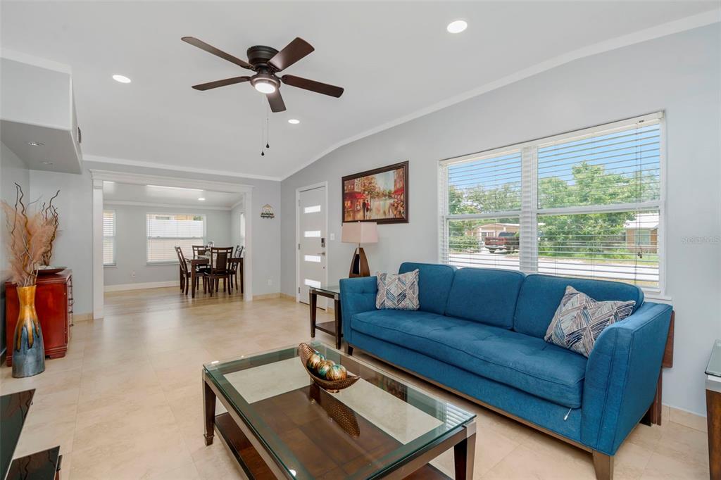 A living room features a blue sofa, a glass coffee table, and an adjacent dining area — 2112 W IDLEWILD AVENUE, TAMPA, FL