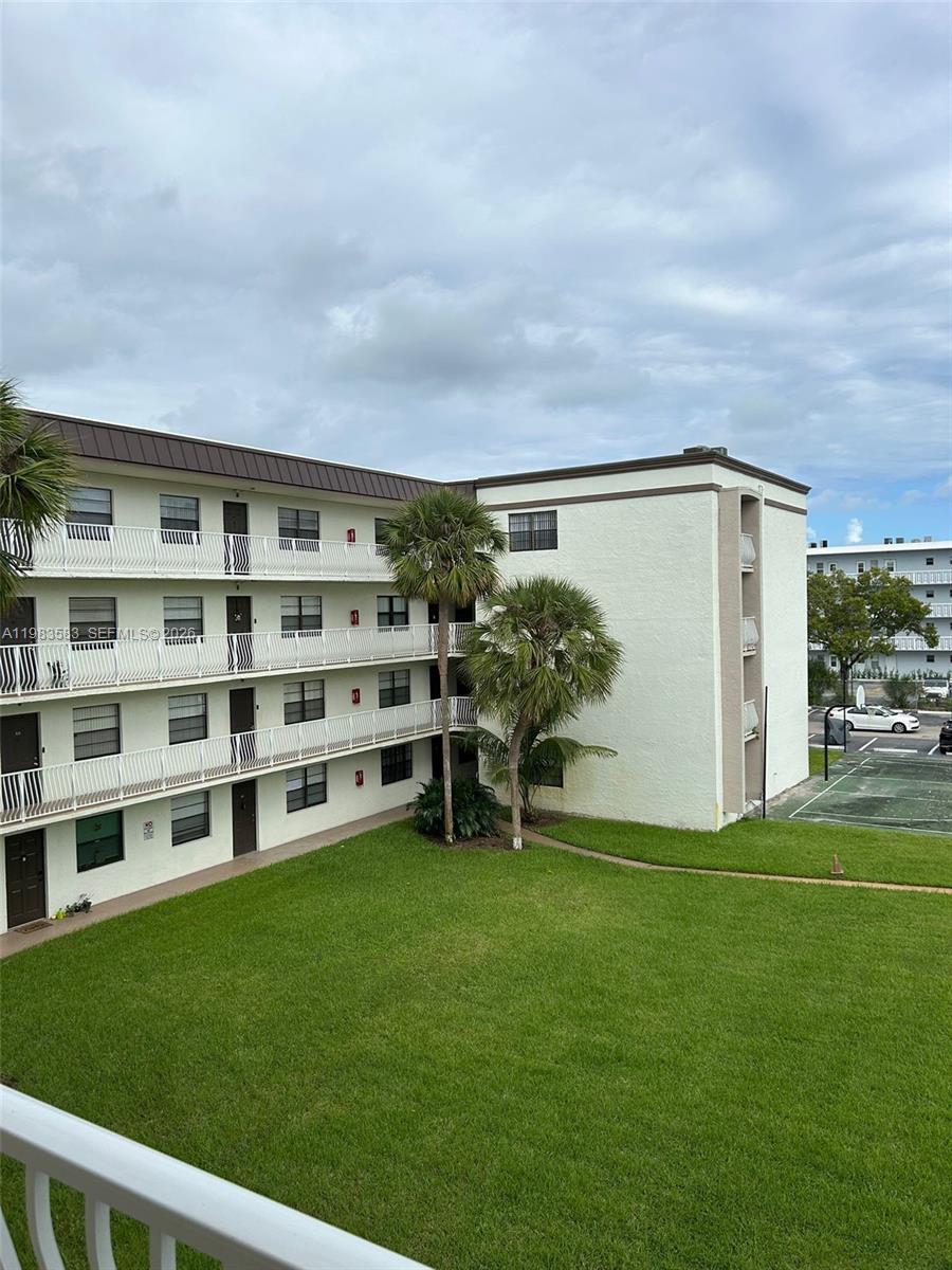 An exterior view of a multi-story apartment building with balconies overlooking a grassy courtyard — 500 NE 2nd St # 310, Dania Beach FL 33004, DANIA BEACH, FL