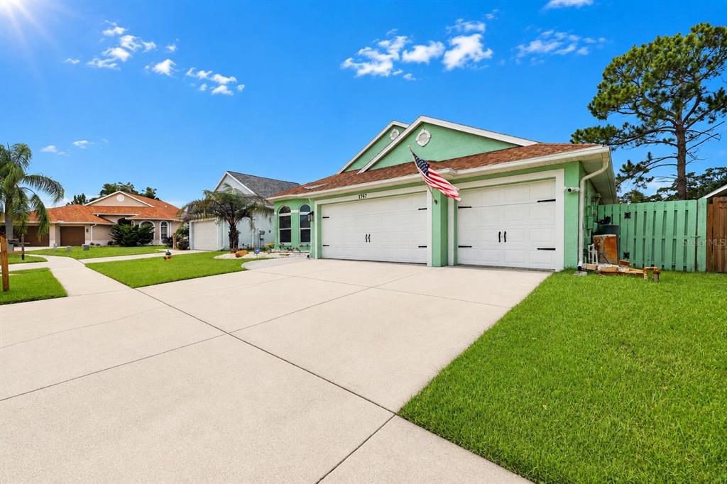 A light green single-story house with a two-car garage and a concrete driveway — 1747 WOOD BROOK STREET, TARPON SPRINGS, FL