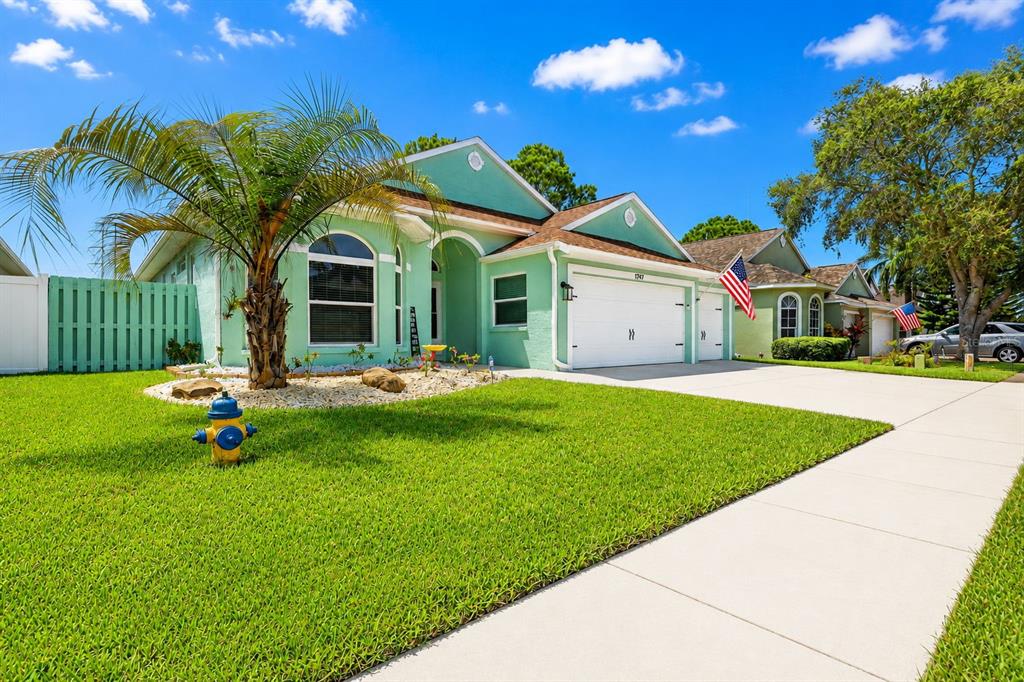 A light green single-story house with a two-car garage and a front yard fire hydrant — 1747 WOOD BROOK STREET, TARPON SPRINGS, FL