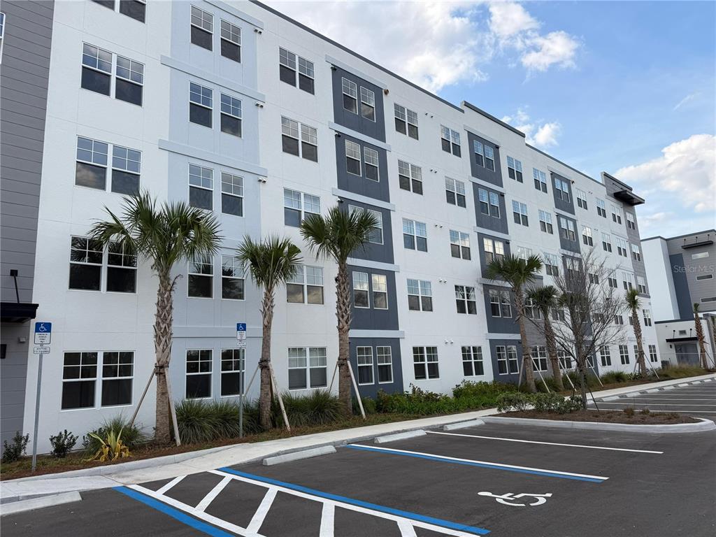 A multi-story apartment building exterior with parking spaces in the foreground — 5587 MILLENIA PARK BOULEVARD UNIT 402, ORLANDO, FL