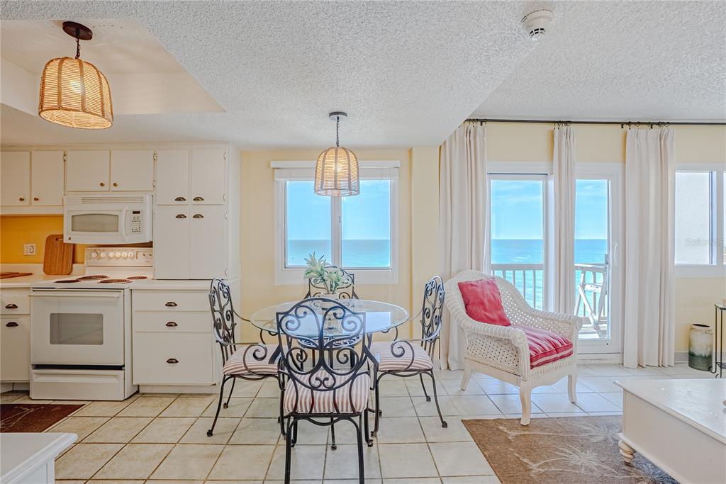 A kitchen and dining area with white cabinets, a glass table, and ocean views — 23223 FRONT BEACH ROAD UNIT 907, PANAMA CITY BEACH, FL