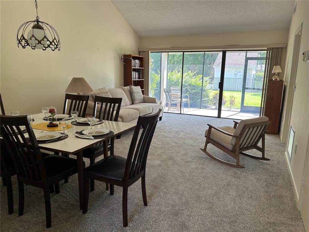 A view from a screened-in porch looking out toward a community pool and lawn — 5204 MYRTLE WOOD UNIT 2, SARASOTA, FL