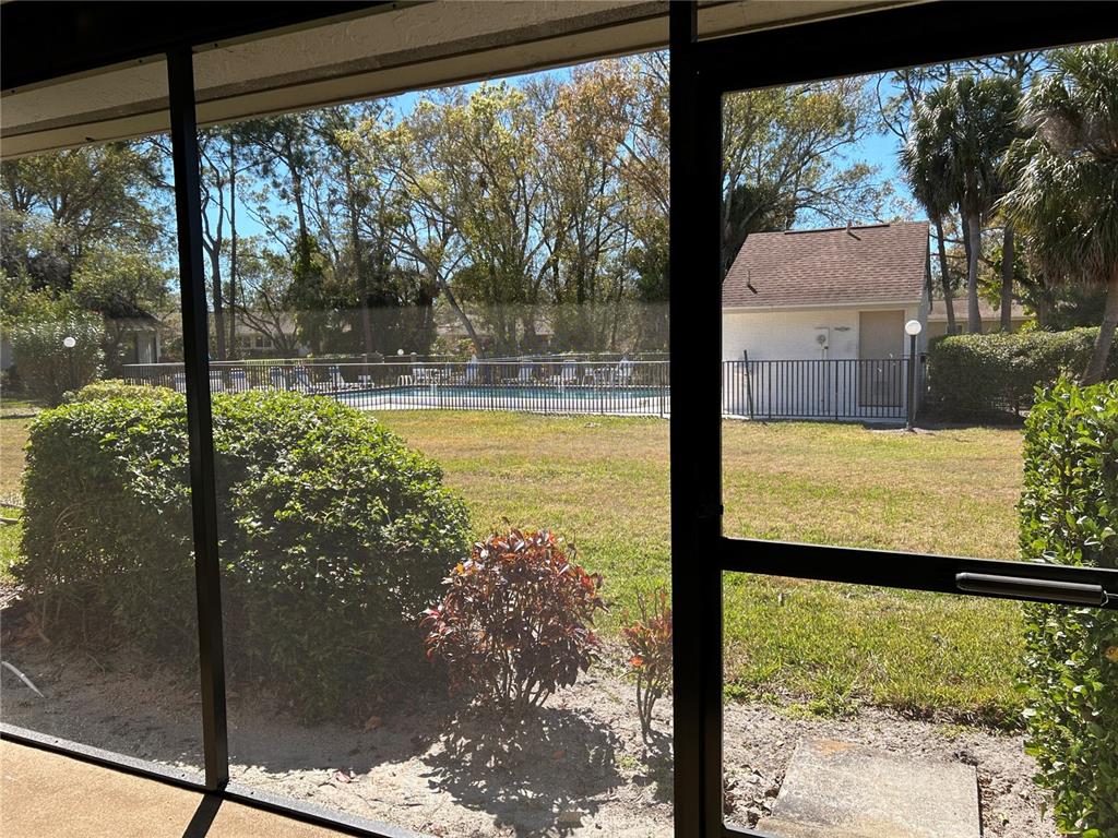 A carpeted room features a tall bookshelf and large sliding glass doors opening to a patio — 5204 MYRTLE WOOD UNIT 2, SARASOTA, FL