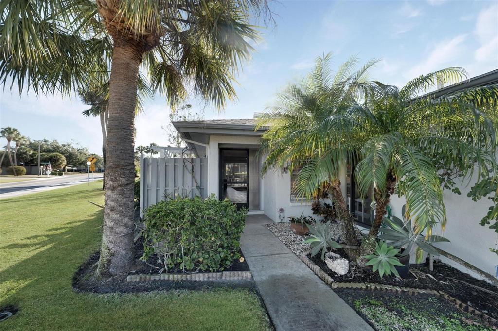 A concrete walkway leads to the front entrance of a house with palm trees — 4201 CENTER GATE LANE UNIT 1, SARASOTA, FL
