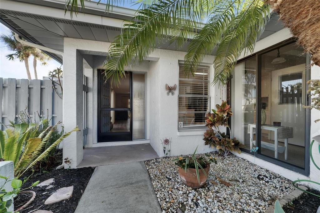A concrete walkway leads to a front entrance with a screen door and gravel landscaping — 4201 CENTER GATE LANE UNIT 1, SARASOTA, FL