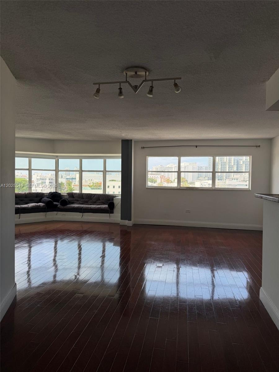 A living room features dark hardwood floors, a track light fixture, and large windows — 1881 Washington Ave # 7C, Miami Beach FL 33139, MIAMI BEACH, FL