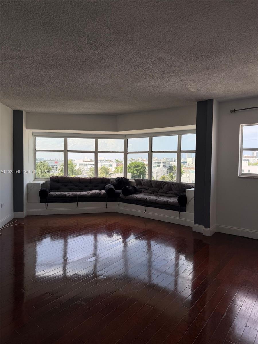 A living room features dark hardwood floors, a built-in window seat, and large panoramic windows — 1881 Washington Ave # 7C, Miami Beach FL 33139, MIAMI BEACH, FL