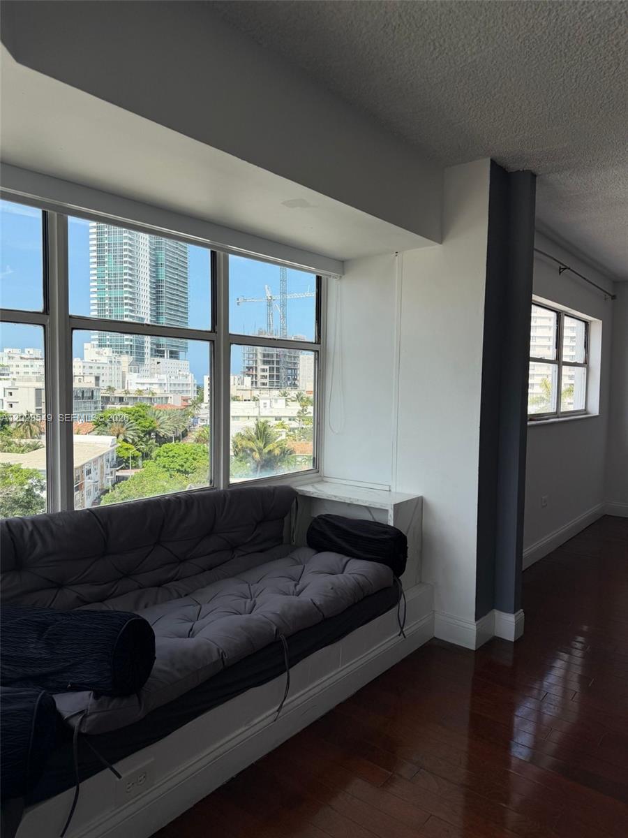 A window seat with a gray cushion sits before a large window overlooking city buildings — 1881 Washington Ave # 7C, Miami Beach FL 33139, MIAMI BEACH, FL