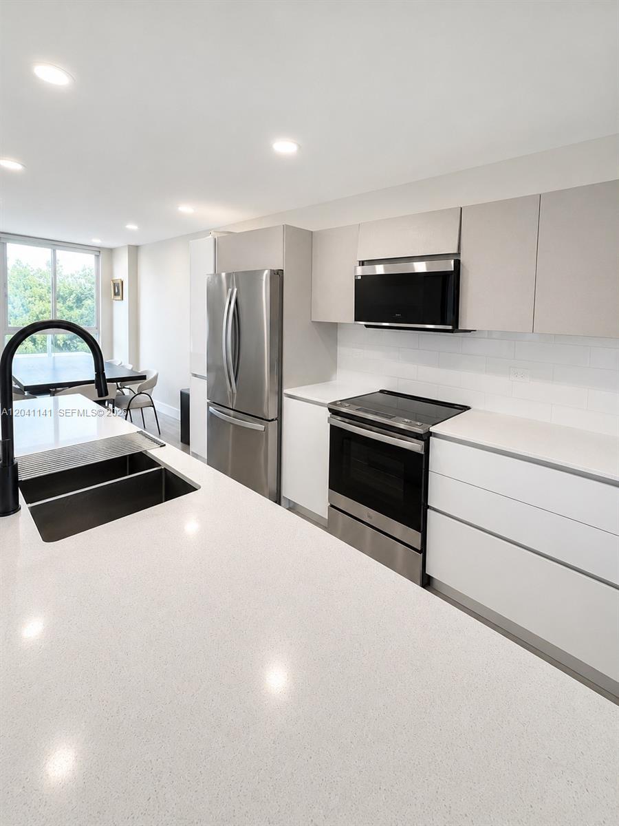 A modern kitchen features white cabinets, quartz countertops, and stainless steel appliances — 2505 NE 193rd St # 4211, Miami FL 33180, MIAMI, FL