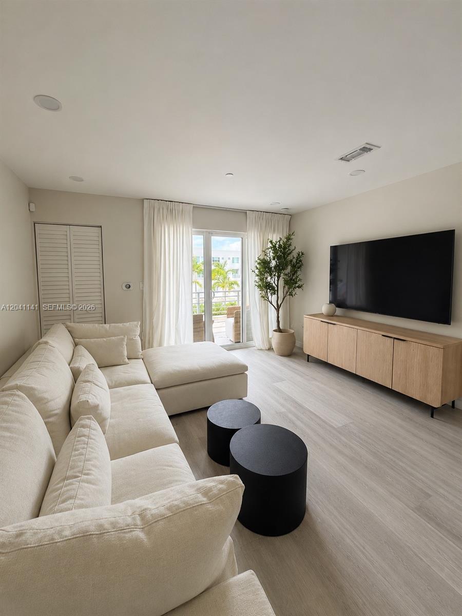 A living room features a cream sectional sofa, two black cylindrical tables, and a television — 2505 NE 193rd St # 4211, Miami FL 33180, MIAMI, FL