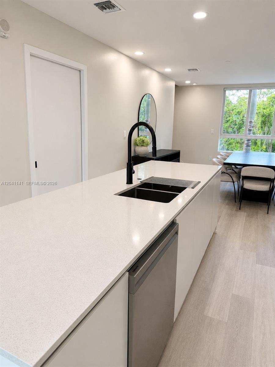 A modern kitchen island with a black faucet and sink sits before a dining area — 2505 NE 193rd St # 4211, Miami FL 33180, MIAMI, FL