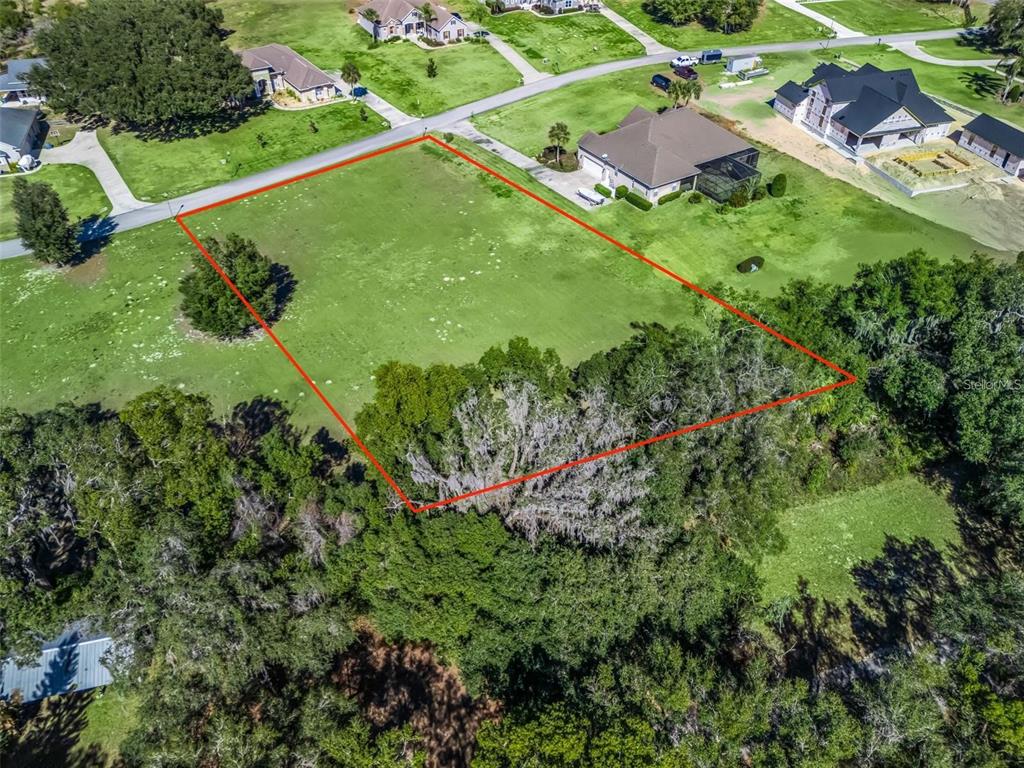 An aerial view shows a vacant, rectangular residential lot outlined in red within a neighborhood — SE 156TH LANE, WEIRSDALE, FL