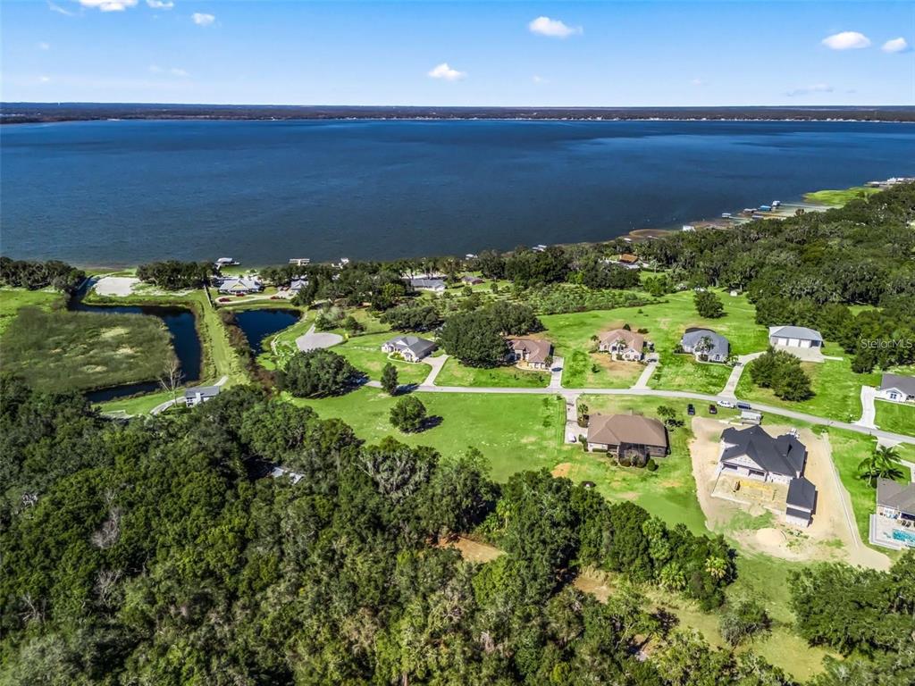 An aerial view shows several houses situated on a grassy lot near a large lake — SE 156TH LANE, WEIRSDALE, FL