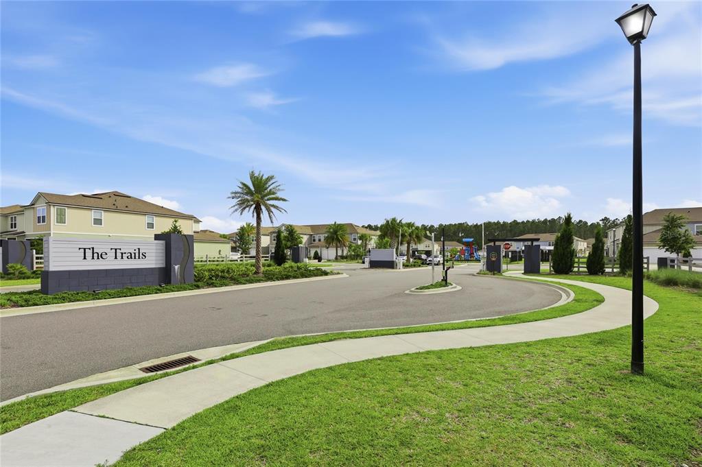 The entrance to The Trails residential community features a sign, palm trees, and a playground — 288 REDBUD ROAD, PALM COAST, FL