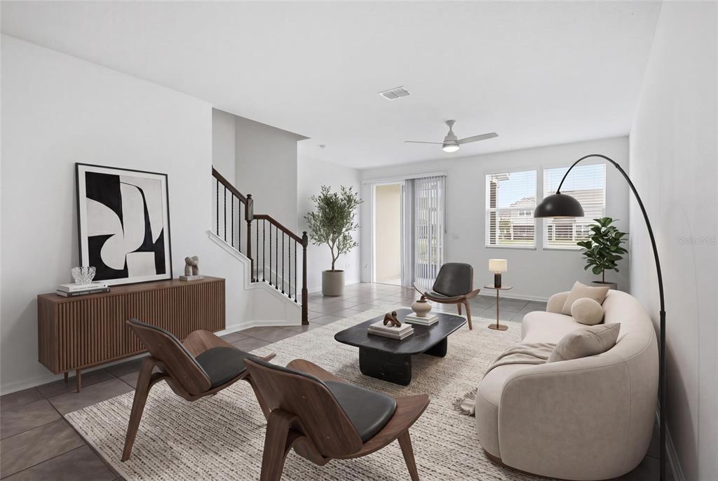 A modern living room features a curved sofa, two wooden chairs, and a staircase — 288 REDBUD ROAD, PALM COAST, FL