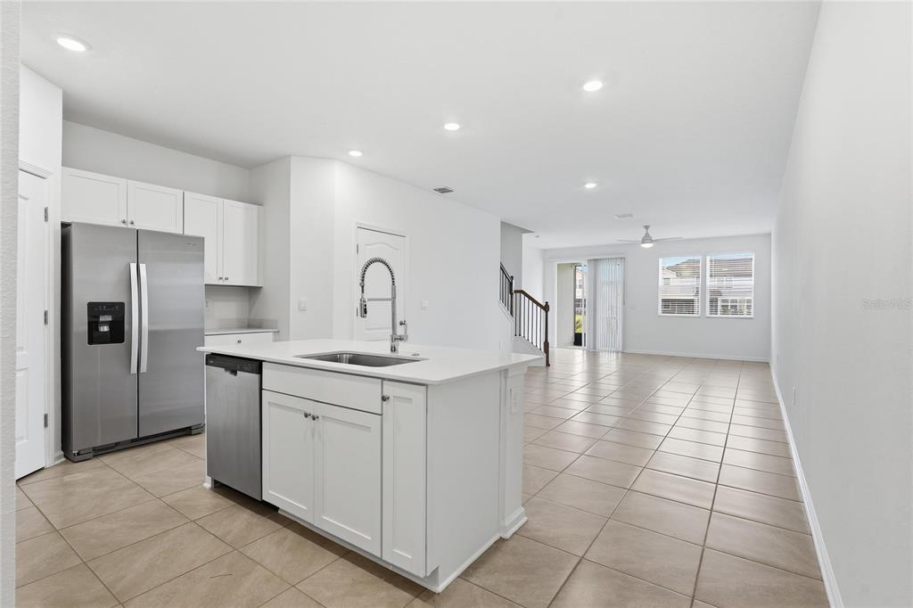A kitchen with white cabinets and a center island opens into a tiled living area — 288 REDBUD ROAD, PALM COAST, FL