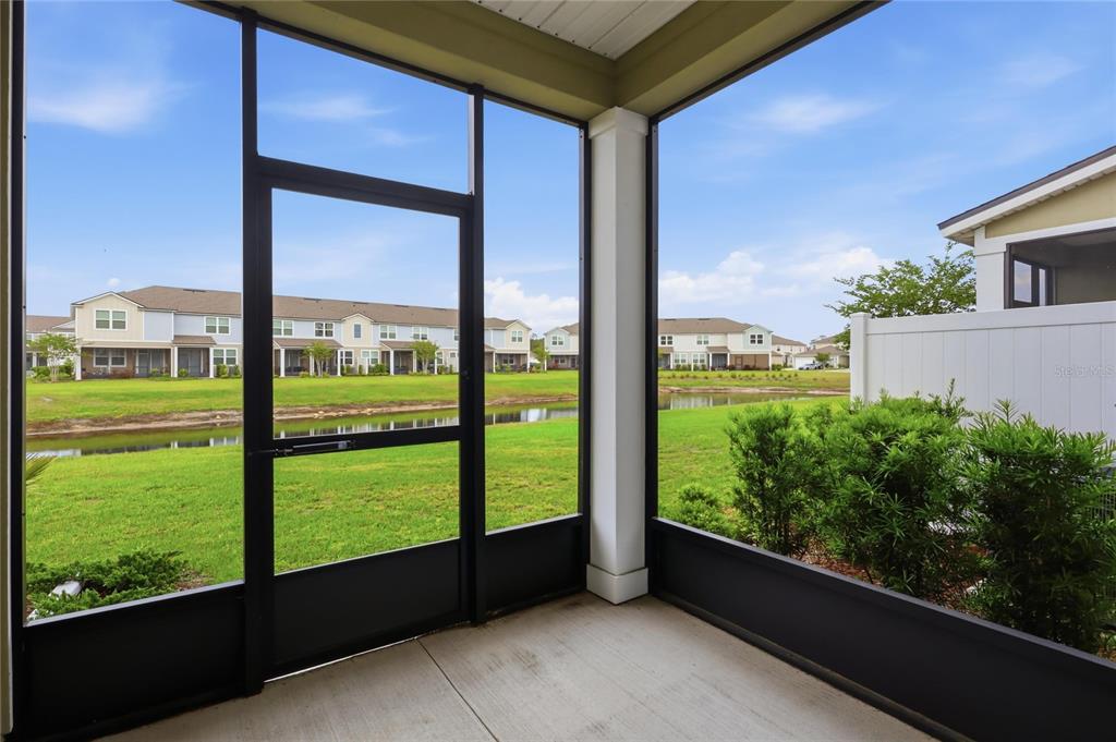 A screened-in porch overlooks a grassy lawn, a small pond, and neighboring townhomes — 288 REDBUD ROAD, PALM COAST, FL