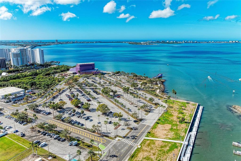 An aerial view shows a large parking lot, a purple building, and a coastal waterfront — 1064 N TAMIAMI TRAIL UNIT 1304, SARASOTA, FL