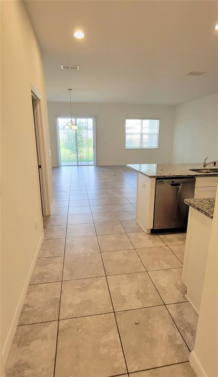 A kitchen with granite countertops and tile flooring opens to a bright living area — 9185 CARMELA AVENUE UNIT 208, DAVENPORT, FL
