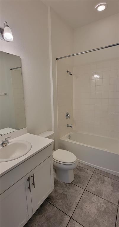 A bathroom features a white vanity with a sink, a toilet, and a tiled shower-tub — 9185 CARMELA AVENUE UNIT 208, DAVENPORT, FL