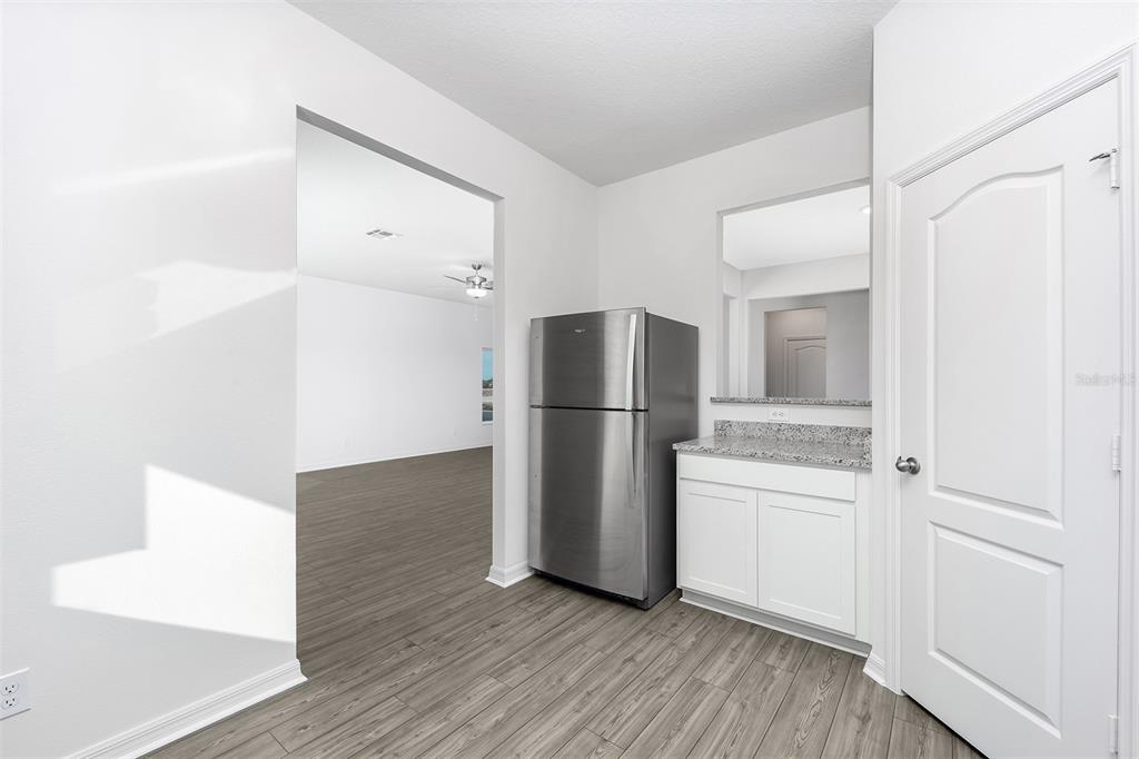 A kitchen area features a stainless steel refrigerator, white cabinets, and granite countertops — 3732 BERGAMOT STREET, LAKE ALFRED, FL