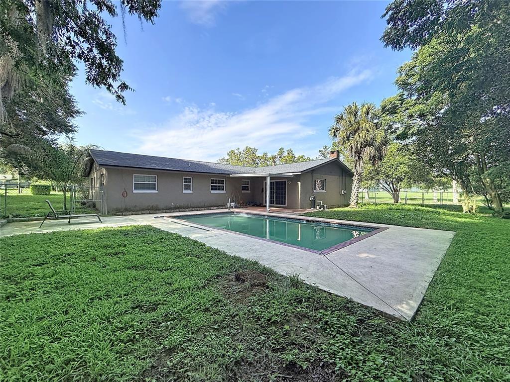 A single-story house with a backyard swimming pool and a concrete patio — 1809 NE 6TH STREET, OCALA, FL