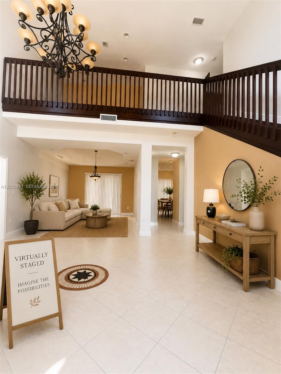 This two-story foyer features a large chandelier, a wooden staircase, and tile flooring — 7856 NW 167th Ter, Miami Lakes FL 33016, MIAMI LAKES, FL