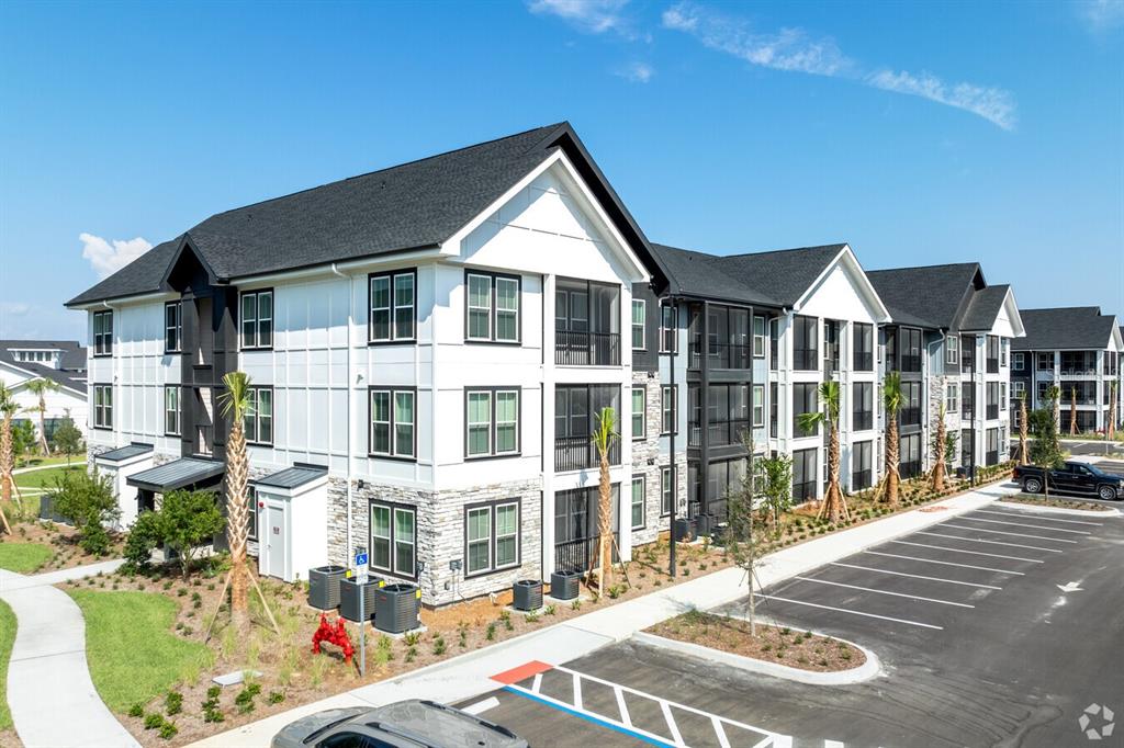 An exterior view of a multi-story apartment building with a parking lot and palm trees — 3020 BASE BOULEVARD UNIT A1, DAVENPORT, FL