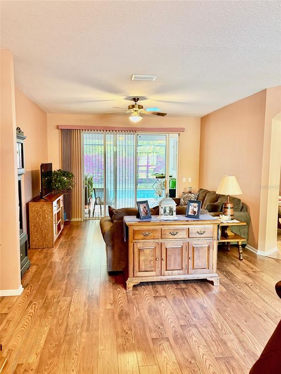 A living room features wood-look flooring, a brown sectional sofa, and a sliding glass door — 18970 SW 99TH STREET, DUNNELLON, FL