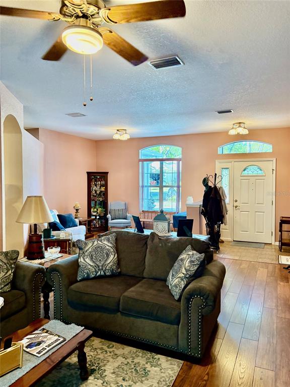 A living room features a brown sofa, a ceiling fan, and a front entry door — 18970 SW 99TH STREET, DUNNELLON, FL