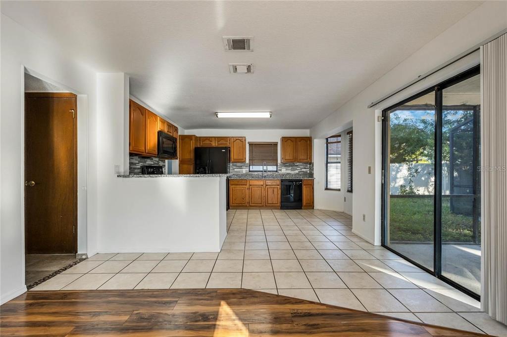 A kitchen with wood cabinets, tile flooring, and a sliding glass door to the backyard — 1450 AMANDA ROAD, KISSIMMEE, FL