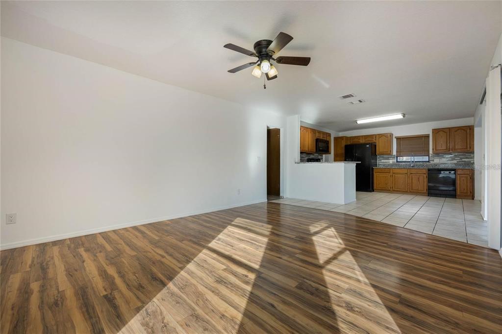 A living room with wood-look flooring transitions into a kitchen with wood cabinets and tile — 1450 AMANDA ROAD, KISSIMMEE, FL