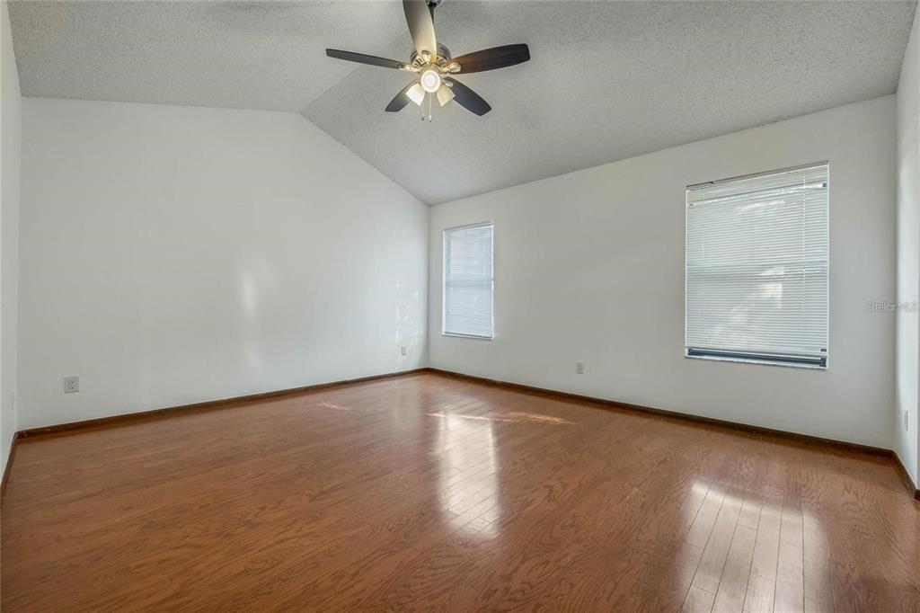 An empty room with wood flooring, white walls, a vaulted ceiling, and a ceiling fan — 1450 AMANDA ROAD, KISSIMMEE, FL