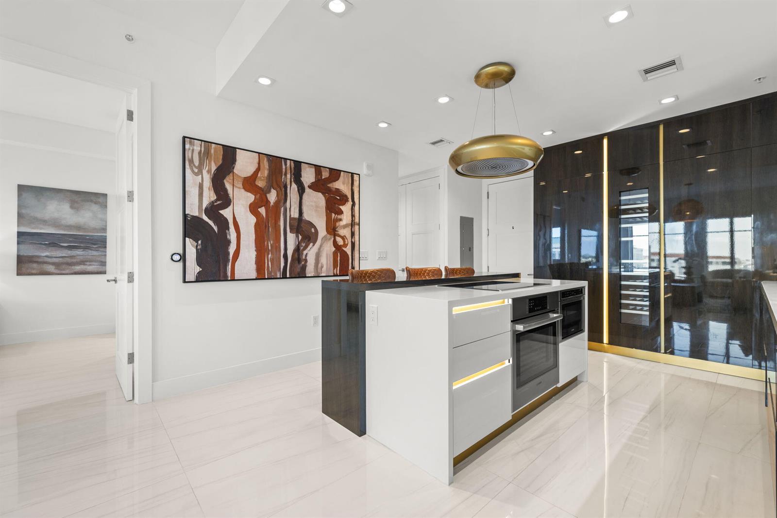 A modern kitchen features a white island with built-in appliances and dark wood cabinetry — 155 E Boca Raton Road # 919, Boca Raton FL 33432, BOCA RATON, FL