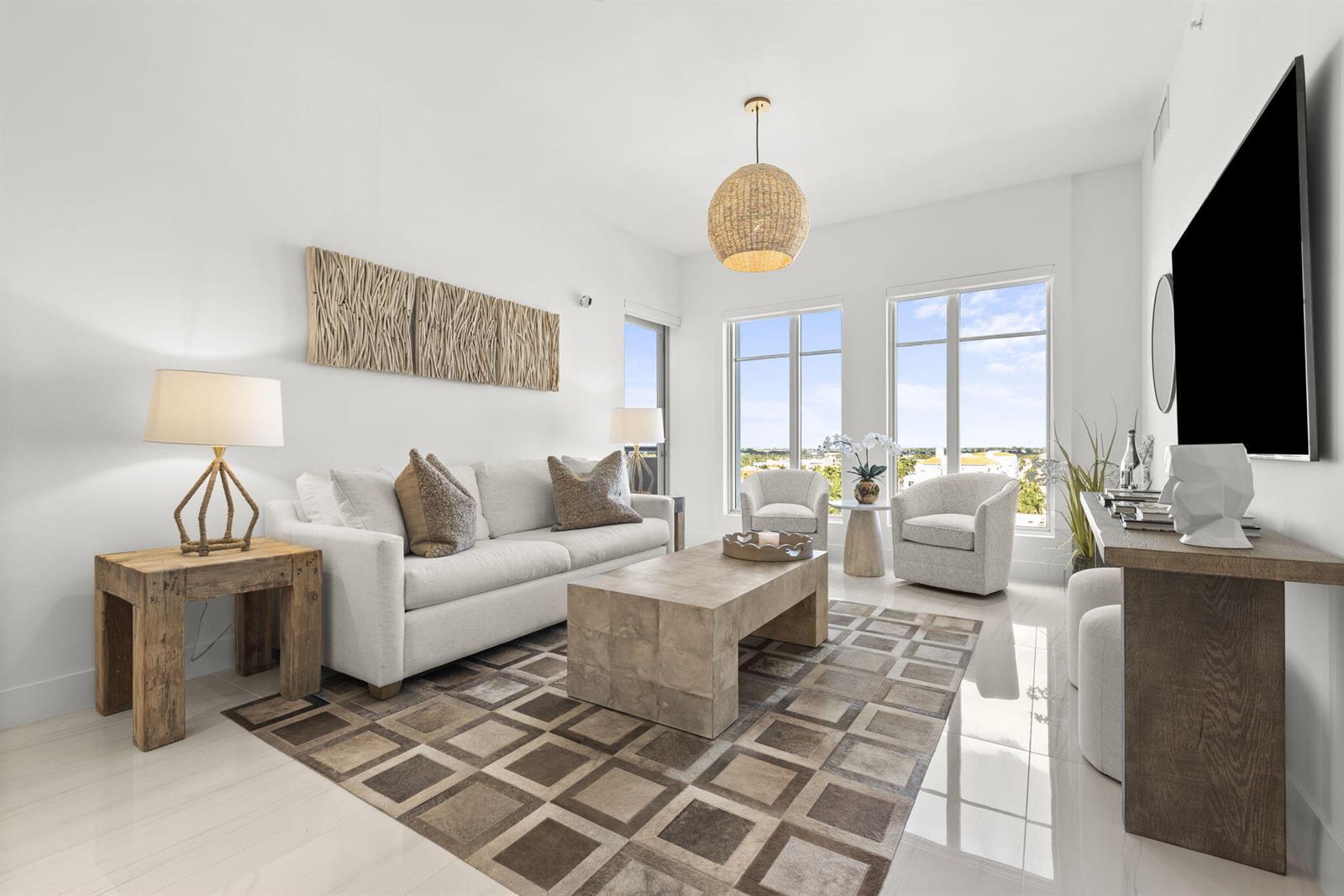 A bright living room features a white sofa, patterned area rug, and large windows — 155 E Boca Raton Road # 919, Boca Raton FL 33432, BOCA RATON, FL