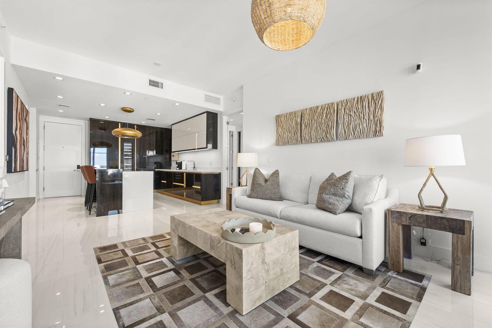 A modern living room with a white sofa, stone coffee table, and an open kitchen — 155 E Boca Raton Road # 919, Boca Raton FL 33432, BOCA RATON, FL