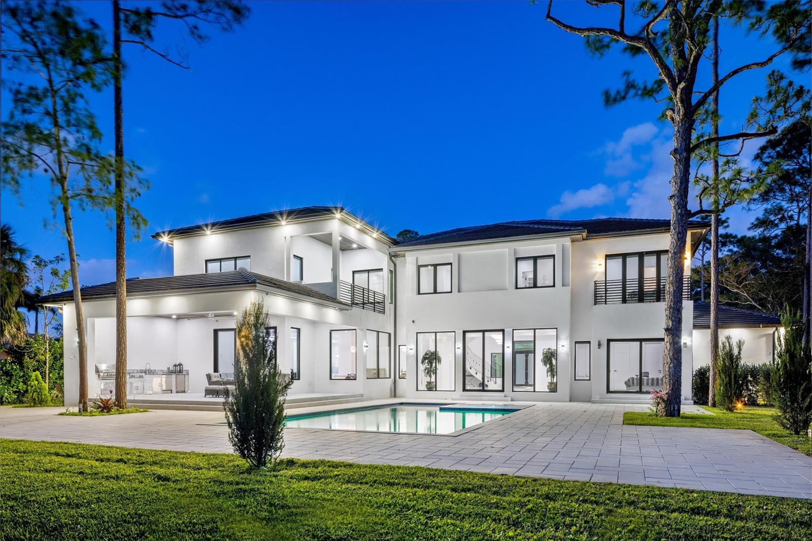 A two-story white modern house with a swimming pool and patio at twilight — 5951 NW 72 Way, Parkland FL 33067, PARKLAND, FL