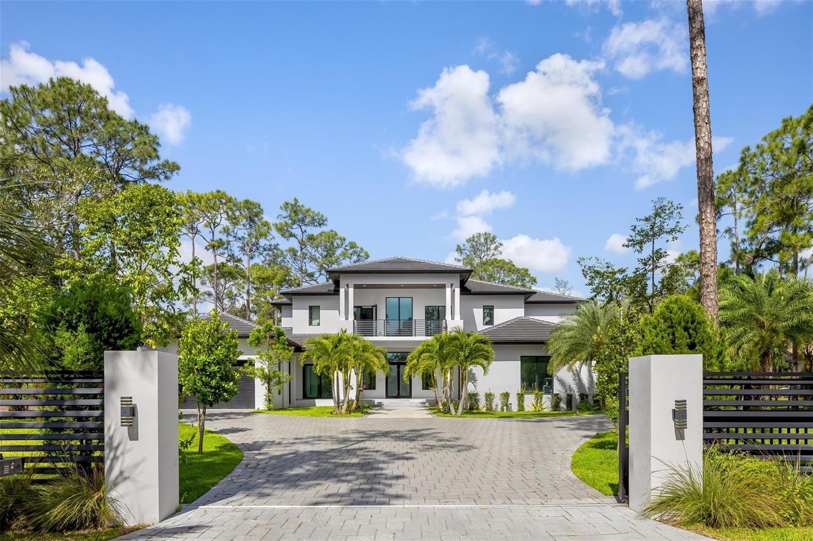 A two-story modern house with a paved driveway and gated entrance surrounded by palm trees — 5951 NW 72 Way, Parkland FL 33067, PARKLAND, FL