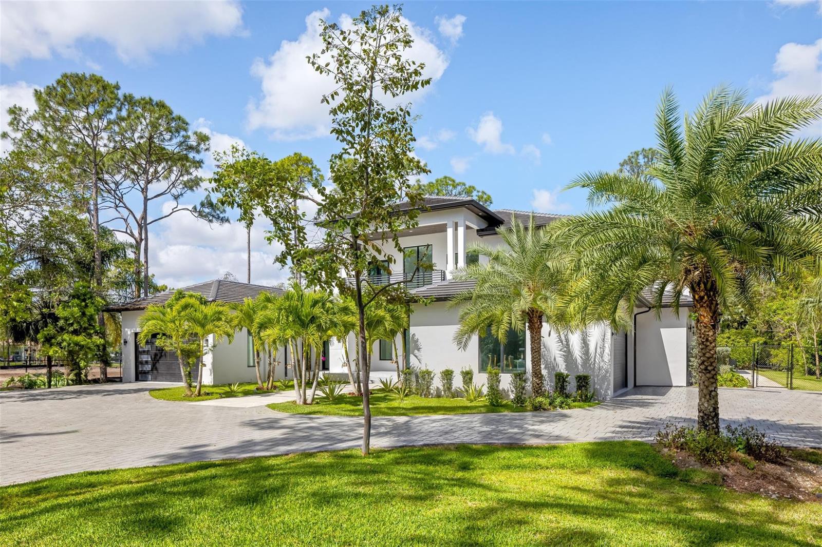 A two-story white modern house features a paved driveway, palm trees, and a green lawn — 5951 NW 72 Way, Parkland FL 33067, PARKLAND, FL