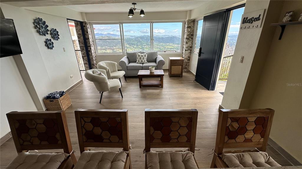 A living room with a mountain view, wood-look tile floors, and four dining chairs — JAMACA DE DIOS CARRETERA PALO BLANCO, JARABACOA, KY