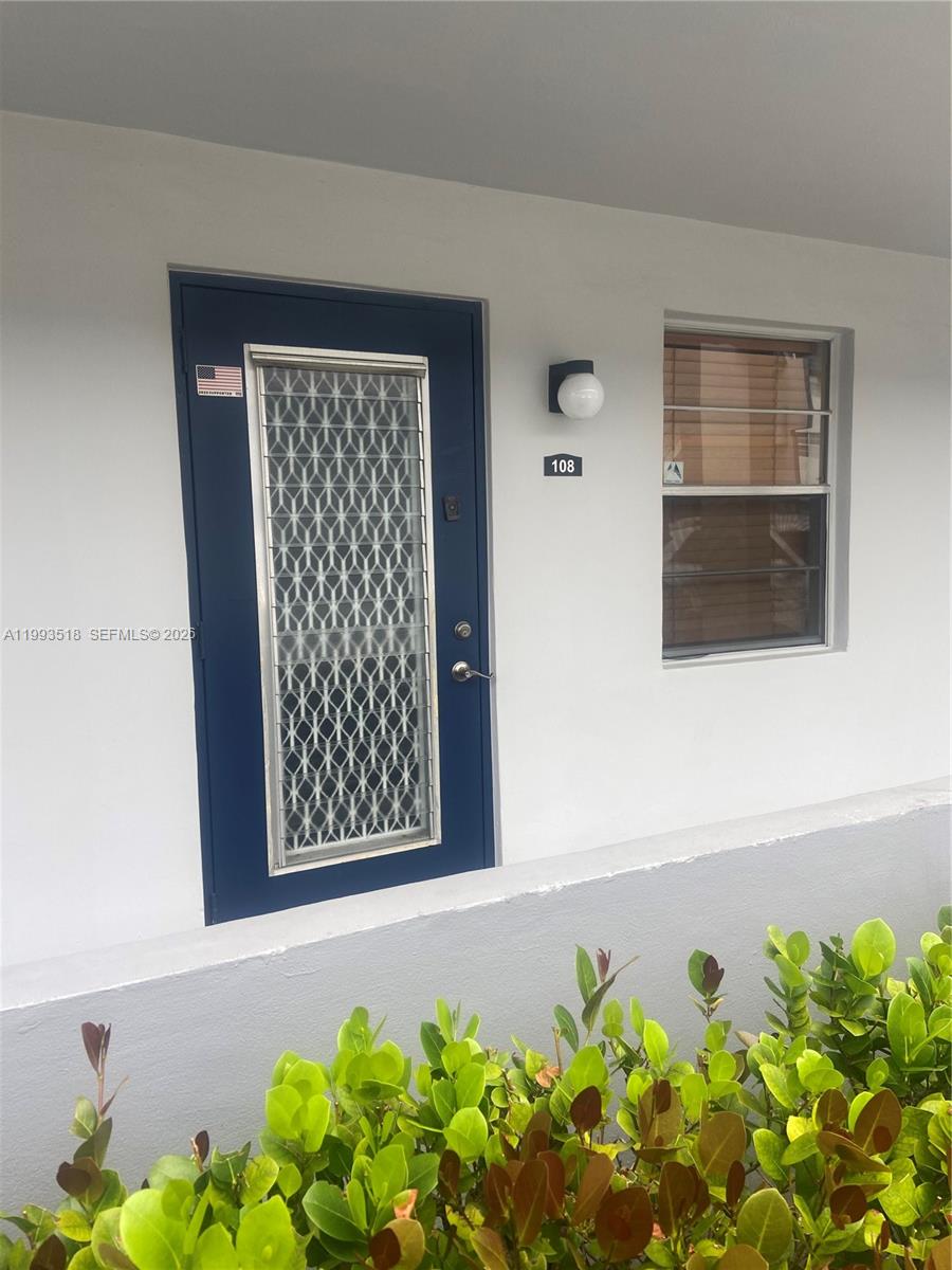 A blue front door with a security grate and a window are on a white wall — 7897 Golf Cir Dr # 108, Margate FL 33063, MARGATE, FL
