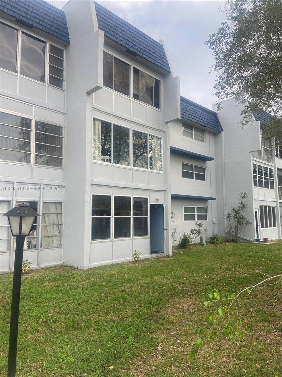 A three-story apartment building with gray stucco walls and blue mansard roof sections — 7897 Golf Cir Dr # 108, Margate FL 33063, MARGATE, FL