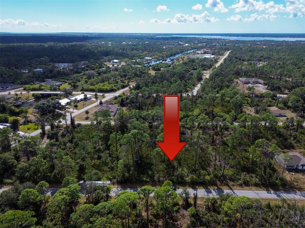 An aerial view shows a wooded, undeveloped residential lot marked by a large red arrow — 13345 HARTH AVENUE, PORT CHARLOTTE, FL