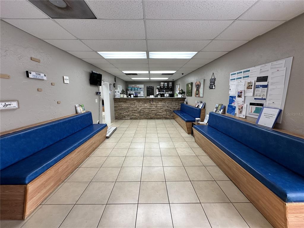 A veterinary office waiting room features blue bench seating, tile flooring, and a reception desk — 1104 S NOVA ROAD, ORMOND BEACH, FL