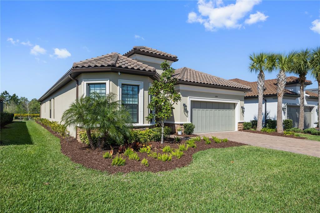 A single-story house with a tile roof, light-colored stucco walls, and a two-car garage — 11414 JUGLANS DRIVE, ODESSA, FL