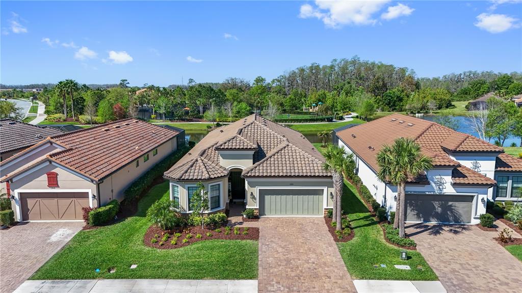 An aerial view shows three suburban houses with tiled roofs and paved driveways — 11414 JUGLANS DRIVE, ODESSA, FL