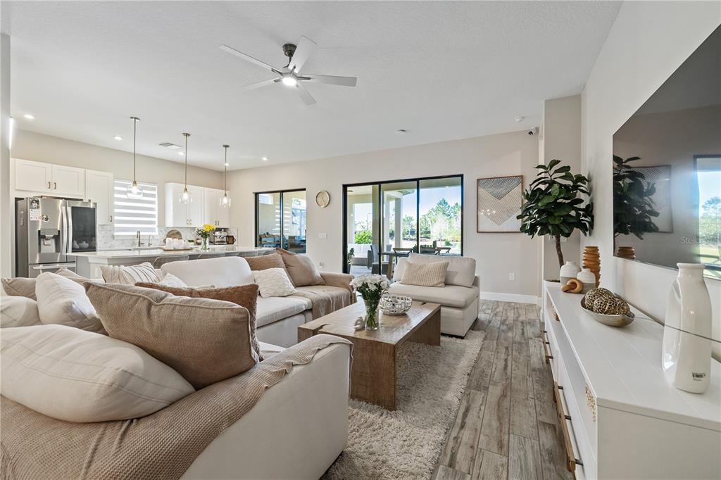 A bright living room features a white sectional sofa, wood coffee table, and open kitchen — 11414 JUGLANS DRIVE, ODESSA, FL