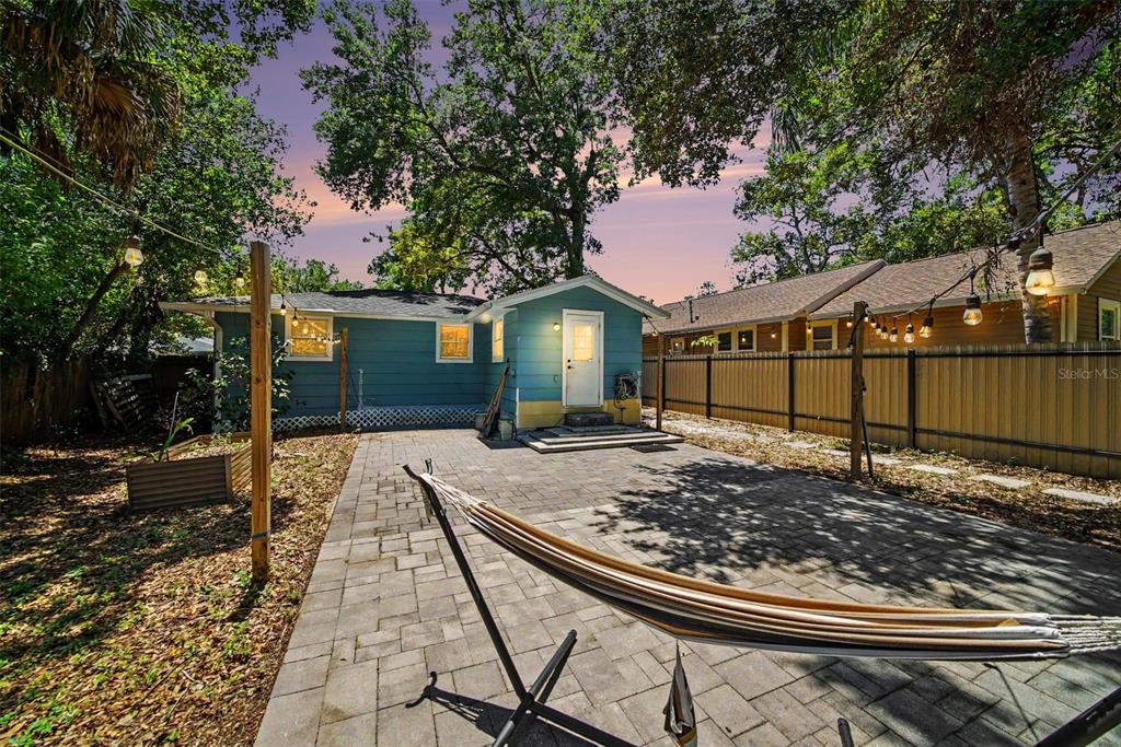 A backyard features a blue house, a paved patio, a hammock, and string lights — 1016 E EMMA STREET, TAMPA, FL