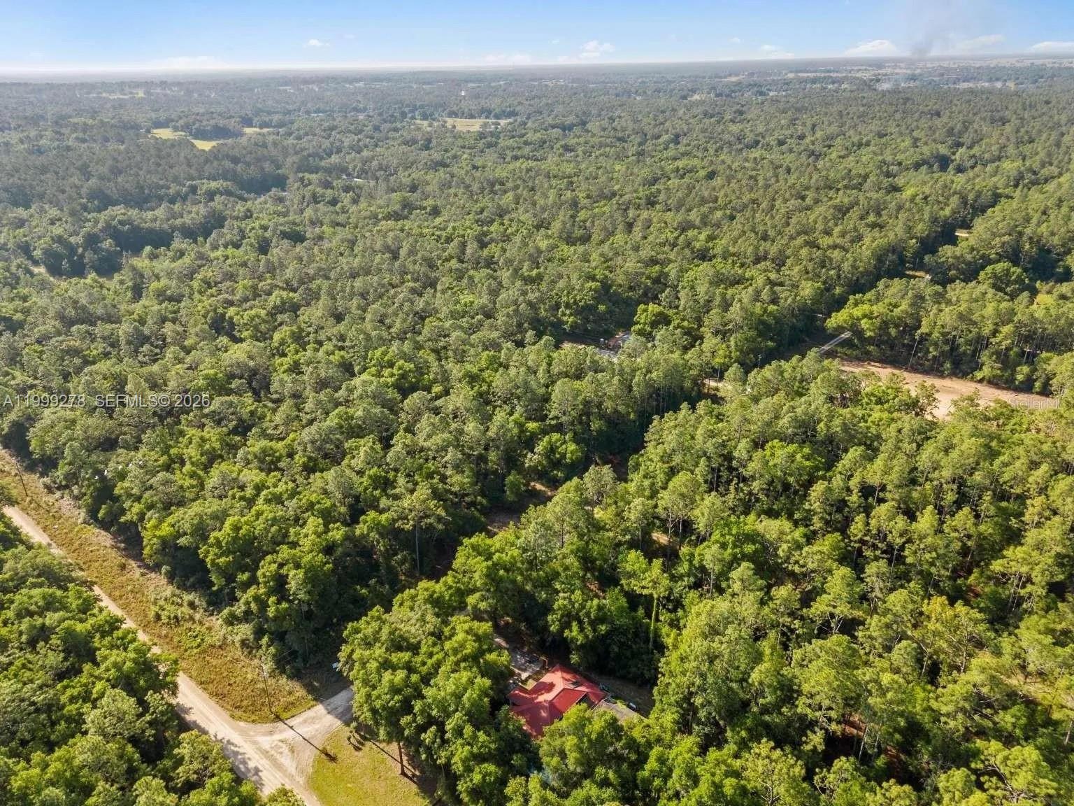 An aerial view shows a house with a red roof surrounded by dense forest — 0 SW 9th Place, Ocala FL 34481, OCALA, FL